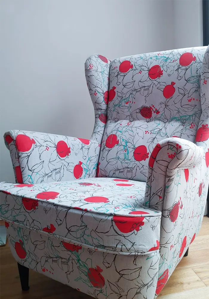 Butaca retapizada con tela blanca y estampados en rojo y negro de granadas
