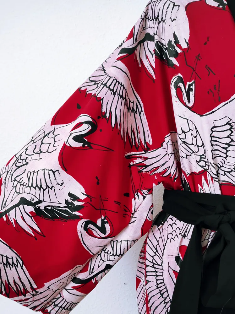 Estampado de la marca Kimonada, se muestra parte de un kimono en color rojo con estampados en blanco y negro de un ave
